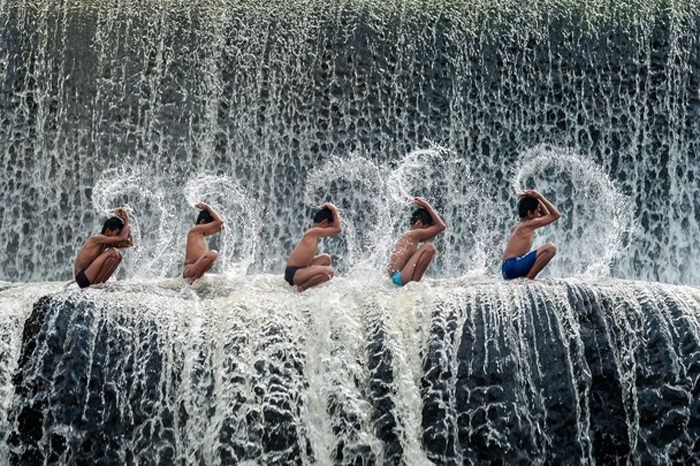 Tampak anak-anak berjejer dan menyiram air ke tubuh mereka masing-masing